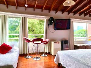 a bedroom with two beds and pink stools in front of windows at Hotel Lleras Premium #1 in Medellín