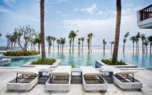 a resort with a pool with palm trees and a beach at Abogo Resort Villas Beachview Da Nang in Danang