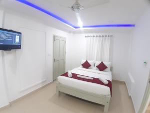 a white bedroom with a bed and a tv at Jyothis Retreat in Palakkad