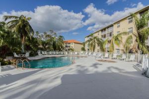 a swimming pool with palm trees and a building at Coral Falls- Celeste Dr./Lely in Belle Meade
