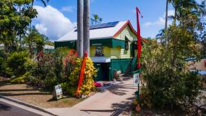 a yellow and green house with red flags in front of it at On The Wallaby Lodge in Yungaburra