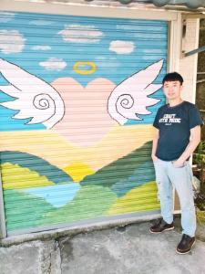 樂野村的住宿－悟 佐茶 Satori tea，站在一堵有翅膀的墙前的年轻人