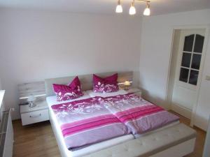 a bedroom with a large bed with pink and purple sheets at Janos-Ferienwohnung-2 in Friedrichsbrunn