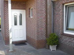 ein Backsteingebäude mit einer weißen Tür und einer Pflanze in der Unterkunft Ferienwohnung Marita in Carolinensiel
