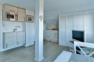 eine Küche mit weißen Schränken und einen TV im Zimmer in der Unterkunft Haus Brönshoog, Appartement 11 in strandnaher Lage in Wenningstedt-Braderup