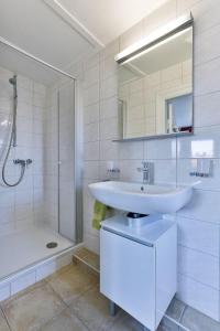 ein weißes Bad mit einem Waschbecken und einer Dusche in der Unterkunft Haus Brönshoog, Appartement 11 in strandnaher Lage in Wenningstedt-Braderup