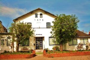 une maison blanche avec des arbres devant dans l'établissement Haus Brönshoog, Appartement 11 in strandnaher Lage, à Wenningstedt