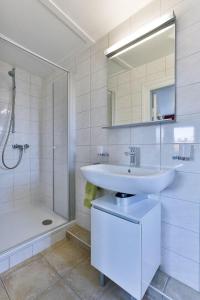 une salle de bain blanche avec lavabo et douche dans l'établissement Haus Brönshoog, Appartement 11 in strandnaher Lage, à Wenningstedt 35 autres photos