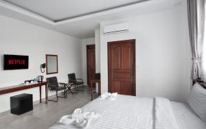 a white bedroom with a bed and a desk at Sandy Residence Sihanoukville in Sihanoukville