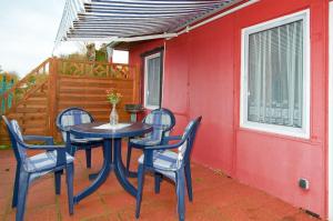 einen Tisch und Stühle auf einer Terrasse mit einer roten Wand in der Unterkunft Ferienwohnung am Berg (2 Erw. & 2 Kinder bis14 Jahre) in Groß Banzelvitz