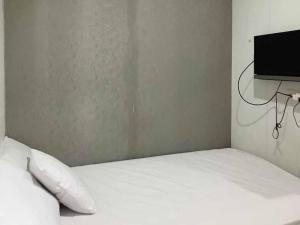 a bedroom with a white bed and a flat screen tv at Hotel Mulia Kendari Mitra RedDoorz in Pipulu