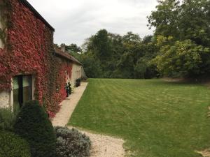 un jardín junto a un edificio con hiedra roja en Domaine des Grattières en Hermonville