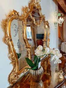 a gold mirror on a table with a vase with flowers at Ai Savi di Venezia in Venice