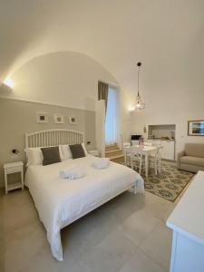 a bedroom with a large white bed and a living room at Domina Living Apartments - Montecucco in Bisceglie