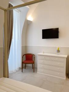 a bedroom with a tv and a chair and a dresser at Domina Living Apartments - Montecucco in Bisceglie
