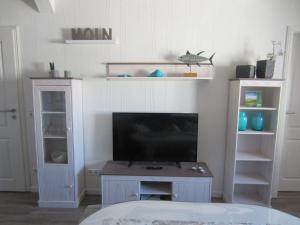 a living room with a flat screen tv and shelves at Ferienwohnung-Oben in Elisabeth-Sophien-Koog