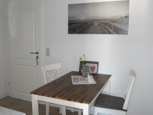 a wooden table with chairs and a picture on the wall at Ferienwohnung-Oben in Elisabeth-Sophien-Koog