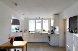 eine Küche mit weißen Schränken, einem Tisch und einem Fenster in der Unterkunft Apartment Close to the Beach in Flensburg