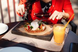 una mujer comiendo un sándwich en una mesa con un vaso de zumo de naranja en Parade Hotel Yaroslavl, en Yaroslavl