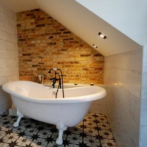 a bath tub in a bathroom with a brick wall at Lychen-Daheim in Lychen
