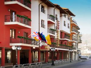 a red and white building with flags on a street at Meridian Hotel Bolyarski in Veliko Tŭrnovo