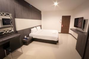 1 dormitorio con 1 cama y TV en Fortune Mansion en Surin