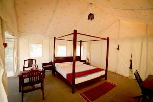 ein Schlafzimmer mit einem Himmelbett in einem Zelt in der Unterkunft Dera Baghdarrah Nature Retreat Udaipur in Udaipur