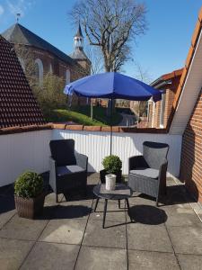 eine Terrasse mit einem Tisch, Stühlen und einem Sonnenschirm in der Unterkunft Ferienzimmer Becker in Werdum