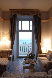 ein Wohnzimmer mit einem Sofa, einem Tisch und einem Fenster in der Unterkunft Hotel De La Ville in Civitavecchia
