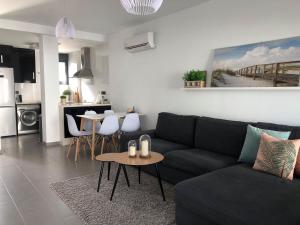 a living room with a black couch and a table at Oasis Beach 1, La Zenia in Playas de Orihuela