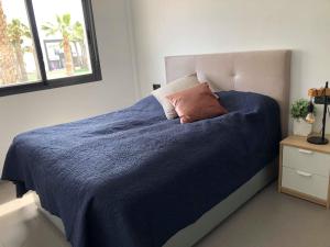 a bedroom with a bed with a blue blanket and a window at Oasis Beach 1, La Zenia in Playas de Orihuela