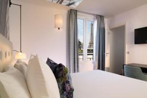 Cette chambre d'hôtel comprend un lit et offre une vue sur la tour Eiffel. dans l'établissement Hôtel Gustave, à Paris