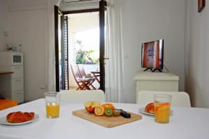 una tavola con un tagliere con frutta e due bicchieri di succo d'arancia di Apartments Omo 1 a Supetar (San Pietro di Brazza)