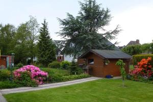 einen Garten mit einer kleinen Holzhütte mit Blumen in der Unterkunft Haus Mueckenberger in Cuxhaven