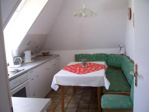 クックスハーフェンにあるHaus-Mueckenbergerのキッチン(テーブル、緑の椅子、白いテーブルクロス付)