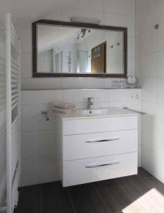 Baño blanco con lavabo y espejo en Ferienwohnung-England, en Nordstrand