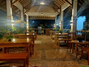 an empty restaurant with wooden tables and chairs at Bale Sebaya Bungalows in Senaru