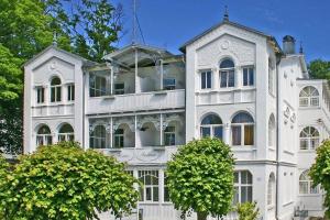 a white building with trees in front of it at Ferienappartement-Moenchgut-21 in Ostseebad Sellin