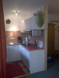 eine kleine Küche mit weißen Schränken und einer Mikrowelle in der Unterkunft Allgäublick App23 Gästehaus in Bad Hindelang in Bad Hindelang
