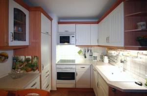 a kitchen with white cabinets and white appliances at Gaestehaeuser-Heidehof-Wohnung-5 in Süderhöft