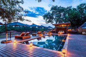 a swimming pool with lounge chairs and a wooden deck at Pafuri Camp in Makuleke Contract Park