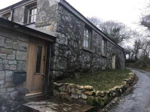 a stone house with a wooden door on a street at Beautifully Converted Chapel in Blisland
