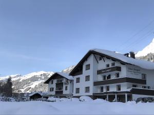 un hôtel dans la neige avec des montagnes en arrière-plan dans l'établissement Haus Zangerl, à Sankt Anton am Arlberg
