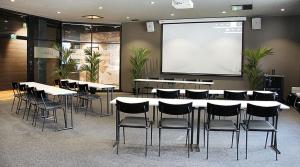 a conference room with tables and chairs and a screen at Original Sokos Hotel Rikala Salo in Salo