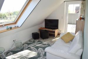 uma sala de estar com um sofá branco e uma televisão em Haus-am-Dorfteich-Kopendorf-Wohnung-2 em Kopendorf