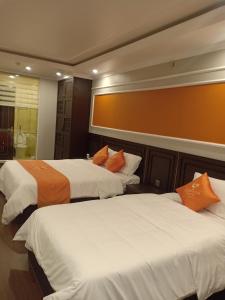 - 2 lits avec des oreillers orange dans une chambre d'hôtel dans l'établissement Sophia Hotel, à Hai Phong