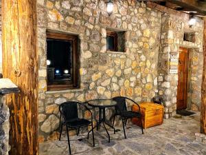a stone wall with a table and chairs in a room at Chalet Kujta in Peje