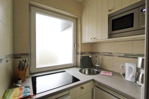 eine kleine Küche mit einer Spüle und einer Mikrowelle in der Unterkunft Sternbild in Hörnum