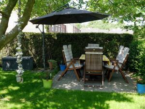 einen Tisch und Stühle unter einem Regenschirm im Hof in der Unterkunft Ferienwohnung Bullerby in Barkelsby