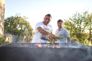 two men are standing next to a grill at Castello di Bossi in Castelnuovo Berardenga